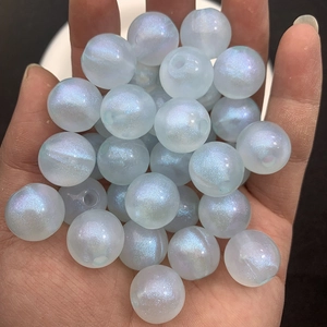 Macro shot of luminous blue DIY beads with iridescent glitter on a person's palm