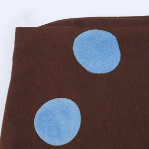Detailed view of coffee brown polka dot fabric with blue patterns and fine texture