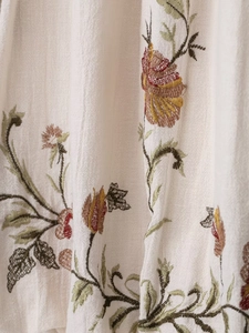 Detailed macro view of colorful floral embroidery on breathable beige cotton-linen fabric