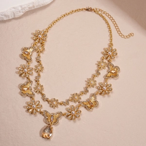 Detail of double-layer gold necklace with butterfly, flower, pearl, and teardrop crystal