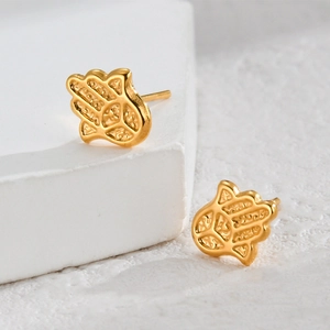 Elegant gold Hamsa Hand stud earrings in stainless steel on white stone background
