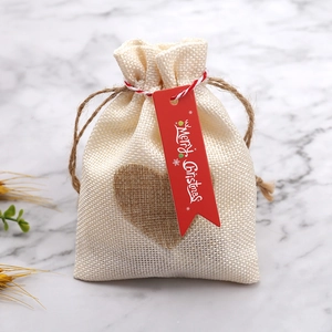 Dettaglio di sacchetto regalo in iuta beige con cuore e targhetta Merry Christmas