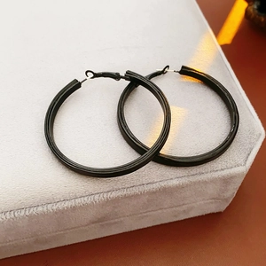 Vue détaillée de créoles rondes en cuir noir sur un écrin à bijoux en velours gris