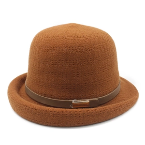 Close-up of knit texture with dark leather strap and golden buckle on brown cloche hat