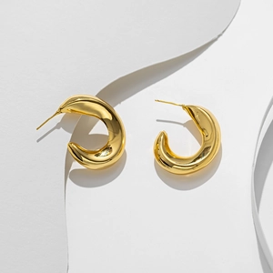 Minimalist thick golden C-shaped hoop earrings with polished finish on geometric background