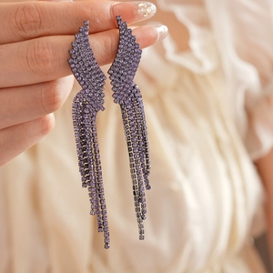 Detailed close-up of purple rhinestone tassel earrings with silver needle and wing design