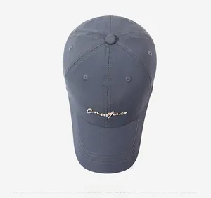 Close-up of dark grey baseball cap with elegant gold cursive Constance embroidery detail