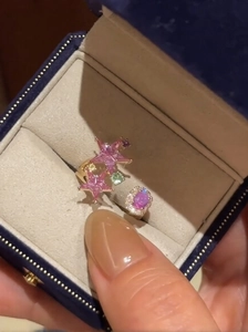 Macro shot of pink star shaped gemstone and small diamonds on a gold open ring
