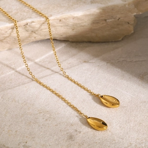 Detailed macro view of 18k gold plated long tassel earrings on a natural stone surface