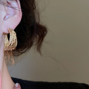 Macro shot of gold-tone textured layered earrings with vintage woven pattern and metallic finish
