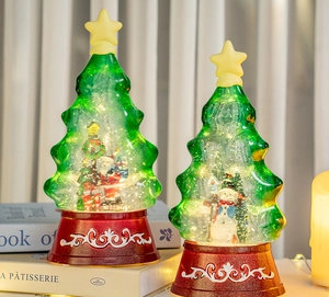 Close-up of lighted Christmas tree water globe with Santa and snowman on vintage red base