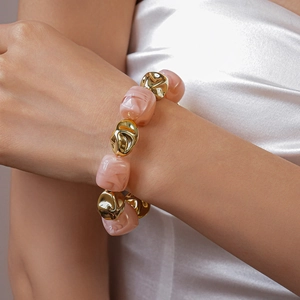 Close-up of pink marbled acrylic geometric beads and gold metallic accents on necklace