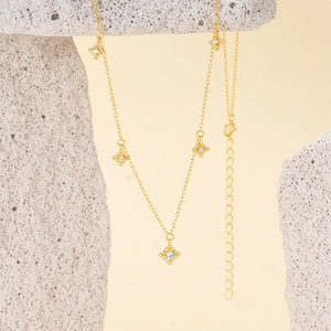 Detailed view of a gold s925 silver star necklace on a white textured stone background