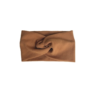 Knitted twist headband in caramel brown with elegant ribbed texture and cross-knot detail