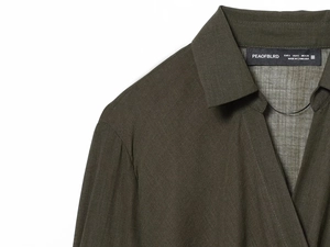 Detail of dark olive green linen shirt showing shoulder seams and collar label