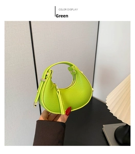 Detail of green crescent bag with pebbled leather texture and gold metal zipper hardware