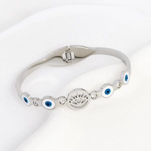 Polished silver evil eye bangle with blue inlay and clear zircons on white background