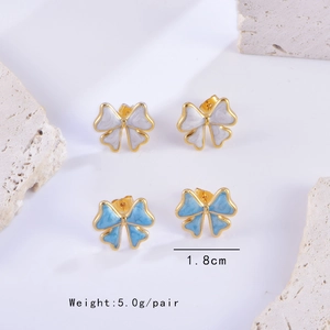 Vue détaillée des boucles d'oreilles nœud blanc et bleu de 1,8 cm sur décor minéral