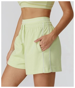 Dettaglio degli shorts sportivi verde chiaro con bordi bianchi, tasche laterali e coulisse