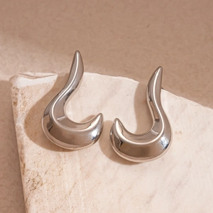 Detail of silver irregular geometric earrings with mirror finish on a natural stone base