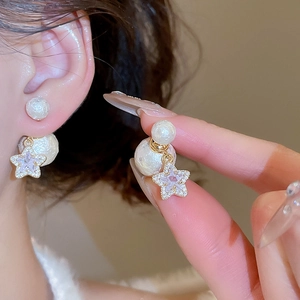 Detail of gold-plated star charm with zircons and double pearl earring design