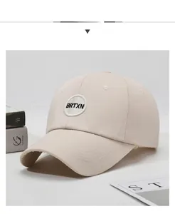Close-up of beige cotton twill baseball cap showing circular BRTXN embroidery and curved brim