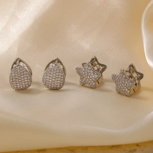 Elegante silberne Stern- und Tropfenohrringe mit Zirkonia auf feinem Seidenhintergrund
