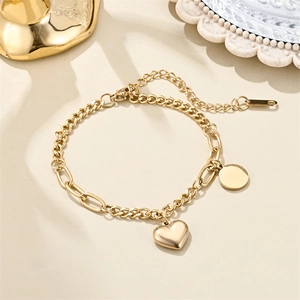 Detail of 18K gold stainless steel chain bracelet with heart charm and round pendant