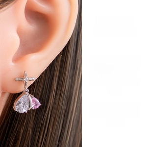 Dettaglio di orecchini a croce con pendenti in zircone a goccia trasparenti e rosa