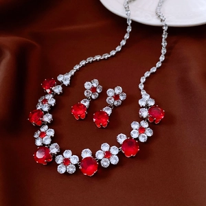 Detail view of flower jewelry set with red and clear stones on brown silk background