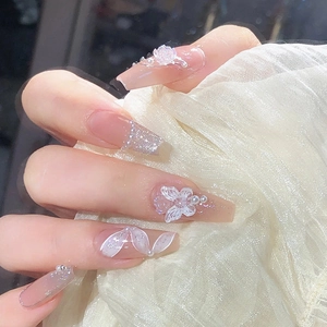 Nude pink press-on nails featuring 3D butterfly, pearls, and glitter gradient accents