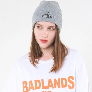 Detail of grey ribbed knit beanie featuring 'good vibes' black cursive embroidery