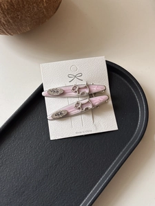 Detail of pink marble texture hair clips with silver puppy charms on a display tray
