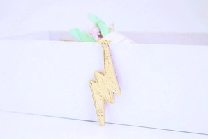 Detailed macro view of a gold-toned lightning bolt keychain with textured finish