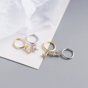 Detail of silver and gold rectangular zircon drop earrings on a white card