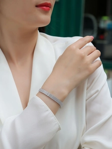 Detail of elegant three-row tennis bracelet in silver finish worn on female wrist