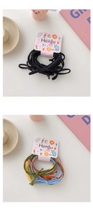 Detail showing elastic hair bands in solid black and assorted bright colors on a desk