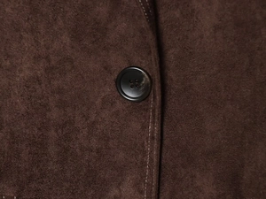 Detailansicht eines schwarzen Knopfes und der Nähte am braunen Blazer aus Wildlederoptik