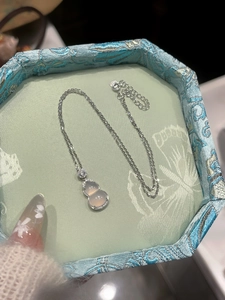 Detailed macro of a silver gourd pendant necklace with crystals in a jewelry box