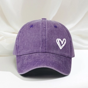 Detailed macro view of heart print and washed denim texture on a purple baseball cap
