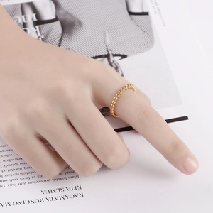 Gros plan d'une bague perlée dorée minimaliste sur un doigt avec un fond de magazine chic