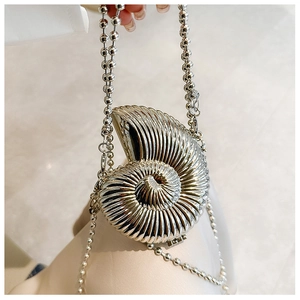Macro detail of silver conch shell evening bag with shiny metallic finish and bead chain