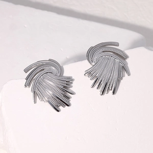 Detailed close-up of vintage silver fan-shaped woven earrings on a white marble background