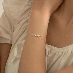 Close-up of a minimalist gold infinity symbol bracelet worn on a woman's wrist