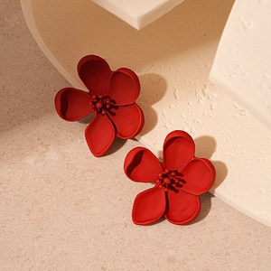 Matte red five-petal flower earrings displayed on a minimalist beige stone texture