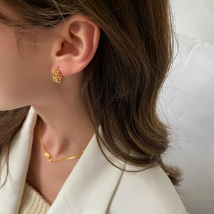 Minimalist gold U-shaped beaded hoop earrings and layered chain necklace on model