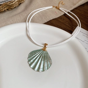 Detail of green iridescent shell pendant with gold edges on white cord choker necklace