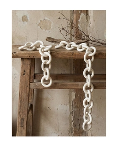 Minimalist white ceramic chain link decor hanging on a vintage wooden bench in wabi-sabi style