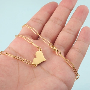 Golden heart pendant on paperclip chain necklace shown in a person's open palm