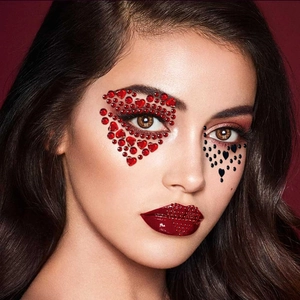 Detailed close-up of red and black heart-shaped face gems crystals on eye and lip makeup